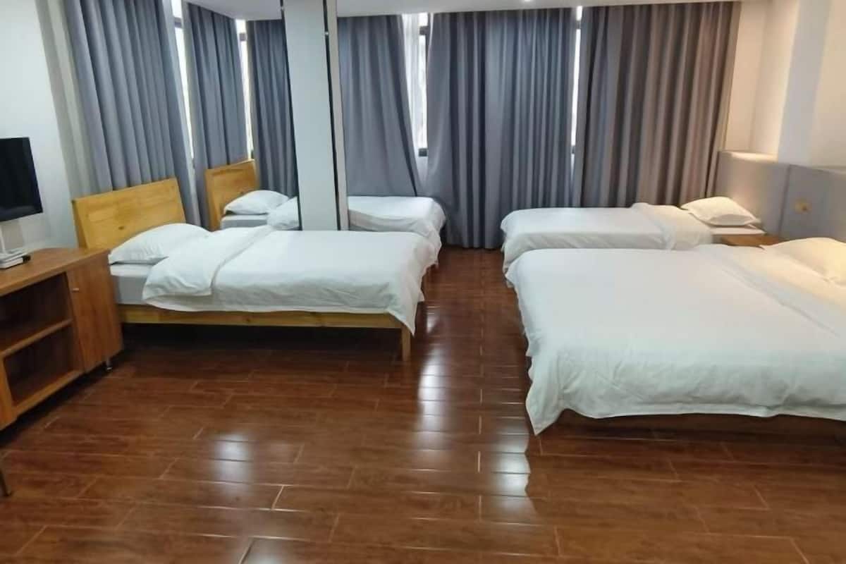 A hotel room with two single beds, a wooden nightstand, a TV, and a wardrobe.