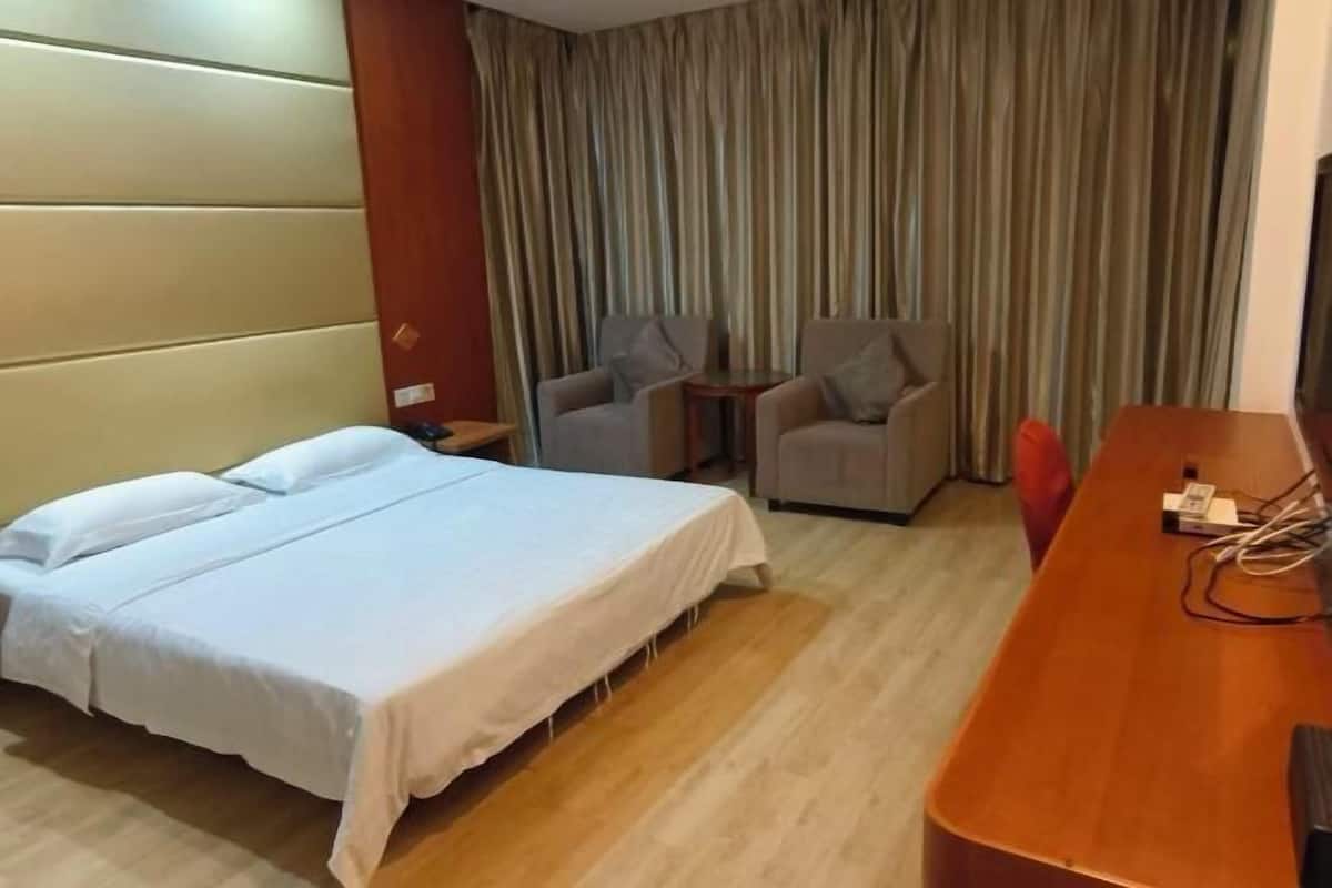 A hotel room with a bed, a desk, a chair, and a curtain.