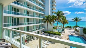 A hotel with multiple balconies, a pool area, and palm trees. - Sorrento JR Ocean View 2 Queen Beds Fontainebleau  (Miami Beach)