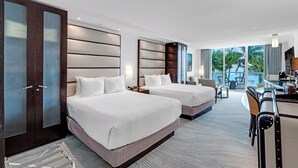 A hotel room with two beds, a desk, and a balcony with a view of palm trees. - Sorrento JR Ocean View 2 Queen Beds Fontainebleau  (Miami Beach)