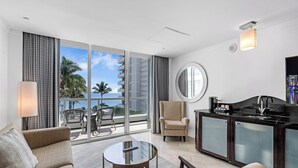 A modern hotel room with a balcony, a round mirror, a sofa, a chair, a small table, and a kitchenette. - Sorrento JR Ocean View 2 Queen Beds Fontainebleau  (Miami Beach)