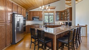 Une cuisine spacieuse dotée de meubles en bois, d’appareils électroménagers en acier inoxydable et d’un grand îlot central avec des tabourets de bar.