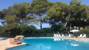 A swimming pool with white lounge chairs and a fence. - Les Pieds Dans L'eau ! (Saint-Raphaël)