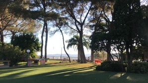 A park with a grassy area, trees, and a distant view of mountains. - Les Pieds Dans L'eau ! (Saint-Raphaël)