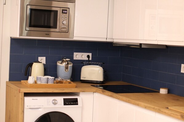 Compact kitchen with a functional layout, featuring a microwave, toaster, and washing machine.