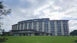 A multi-story hotel with a flat roof and balconies, surrounded by a grassy area. - Newly Renovated Hilo Lagoon 2 BD Condo-A/C, Pool (Hilo)