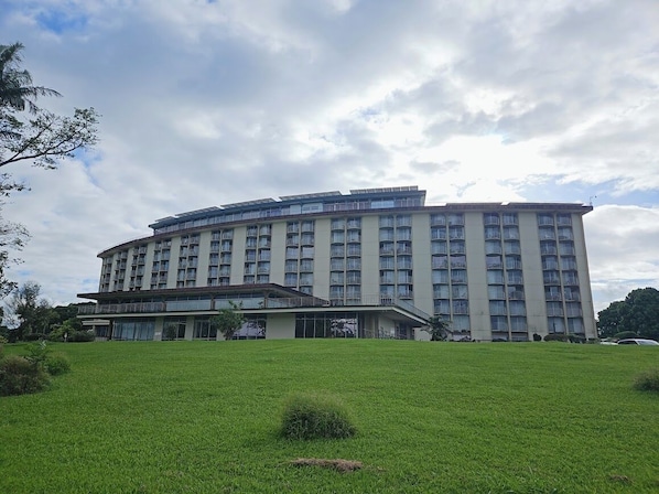A multi-story hotel with a flat roof and balconies, surrounded by a grassy area. - Newly Renovated Hilo Lagoon 2 BD Condo-A/C (Hilo)