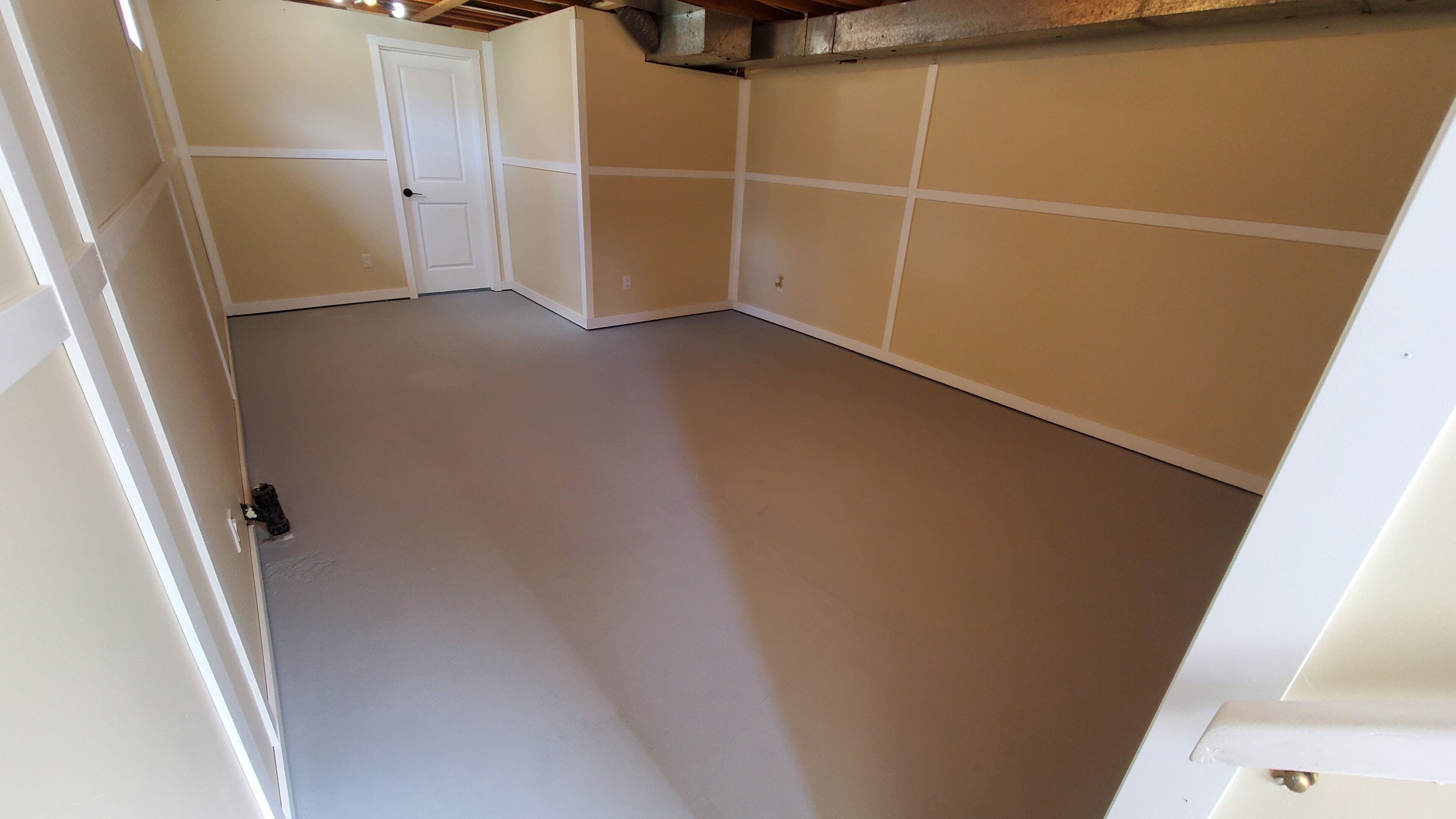 Ein Zimmer mit einer weißen Tür, beige gefärbten Wänden und einem schlichten Boden.