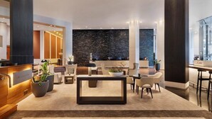 A modern lobby with a reception desk, seating area, and a large black marble wall. - JW Marriott Auckland (Auckland)