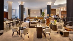 A modern hotel lobby with a central seating area, a bar, and a kitchen visible in the background. - JW Marriott Auckland (Auckland)