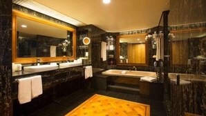 A luxurious bathroom with dark marble walls, multiple sinks, a large mirror, and a yellow patterned floor. - JW Marriott Auckland (Auckland)