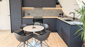 Une cuisine moderne avec des meubles de couleur sombre, une table de salle à manger ronde et des chaises noires.
