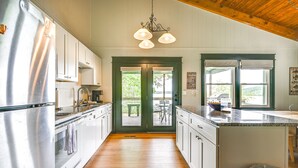A modern kitchen with white cabinets, stainless steel appliances, and a wooden floor.