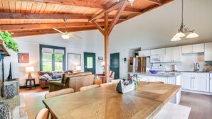 A spacious kitchen with white cabinets, a wooden dining table, and a ceiling fan.