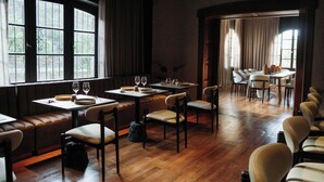 Un restaurante con suelo de madera, mesas, sillas y una zona de estar con bancos.