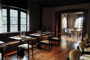 Un restaurante con suelo de madera, mesas, sillas y una zona de estar con bancos.