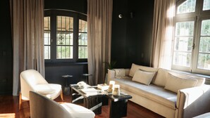 Una sala de estar moderna con un sofá, sillones, una mesa de centro y un amplio ventanal con cortinas.