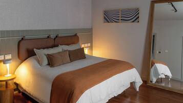 Un lit bien fait, avec une tête de lit marron, une table de chevet avec une lampe et un miroir accroché au mur.