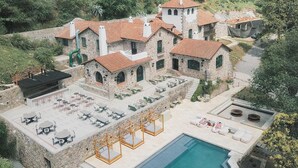 Una villa en la ladera con piscina, mobiliario exterior y arquitectura de piedra.