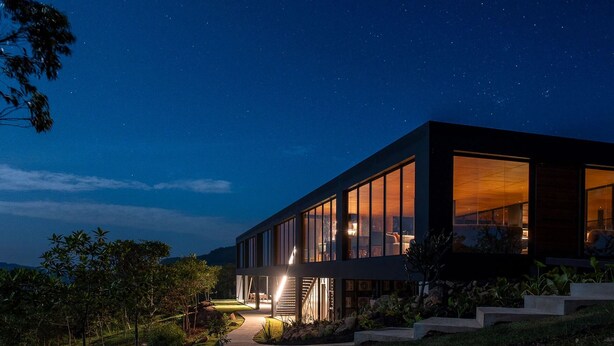 Una casa moderna con ventanas amplias, una entrada iluminada y un jardín ajardinado.