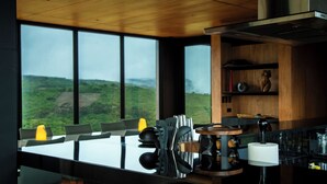 Una cocina moderna con una isla grande, armarios de madera y vistas a un paisaje verde a través de amplios ventanales.