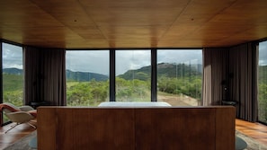 A modern interior with a large wooden ceiling, a central seating area, and expansive windows offering a view of a mountainous landscape. - Montefuego Samaipata (Samaipata)