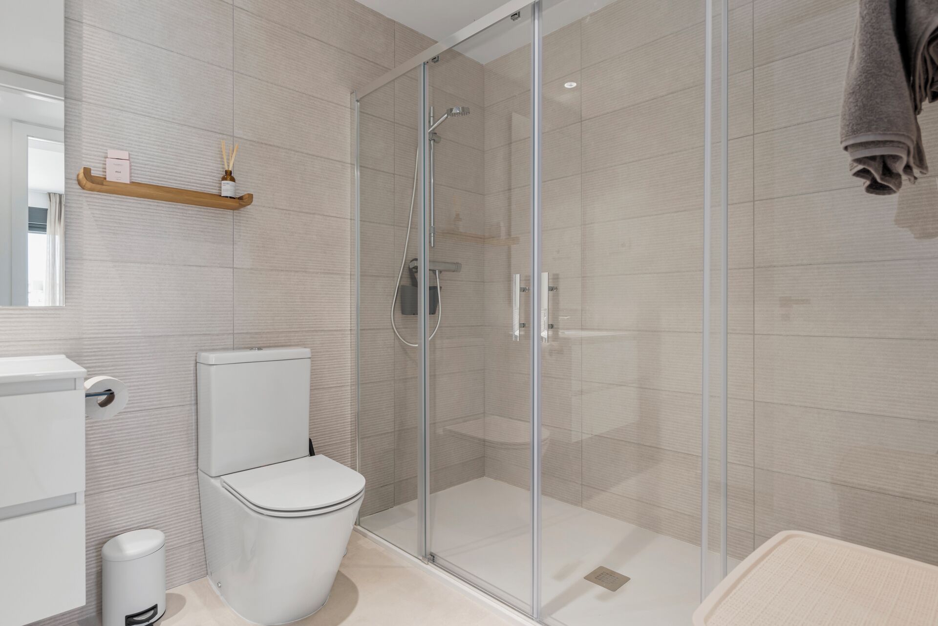 Un baño moderno con ducha de vidrio, inodoro y toallero.