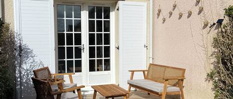 A wooden deck with outdoor furniture, a white door, and a green lawn.