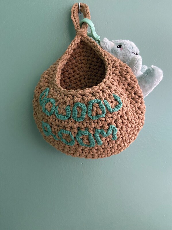 Un sac en crochet avec une anse et un animal en peluche à l’intérieur.