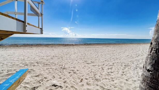 A beach with a lifeguard tower and a clear blue sky.