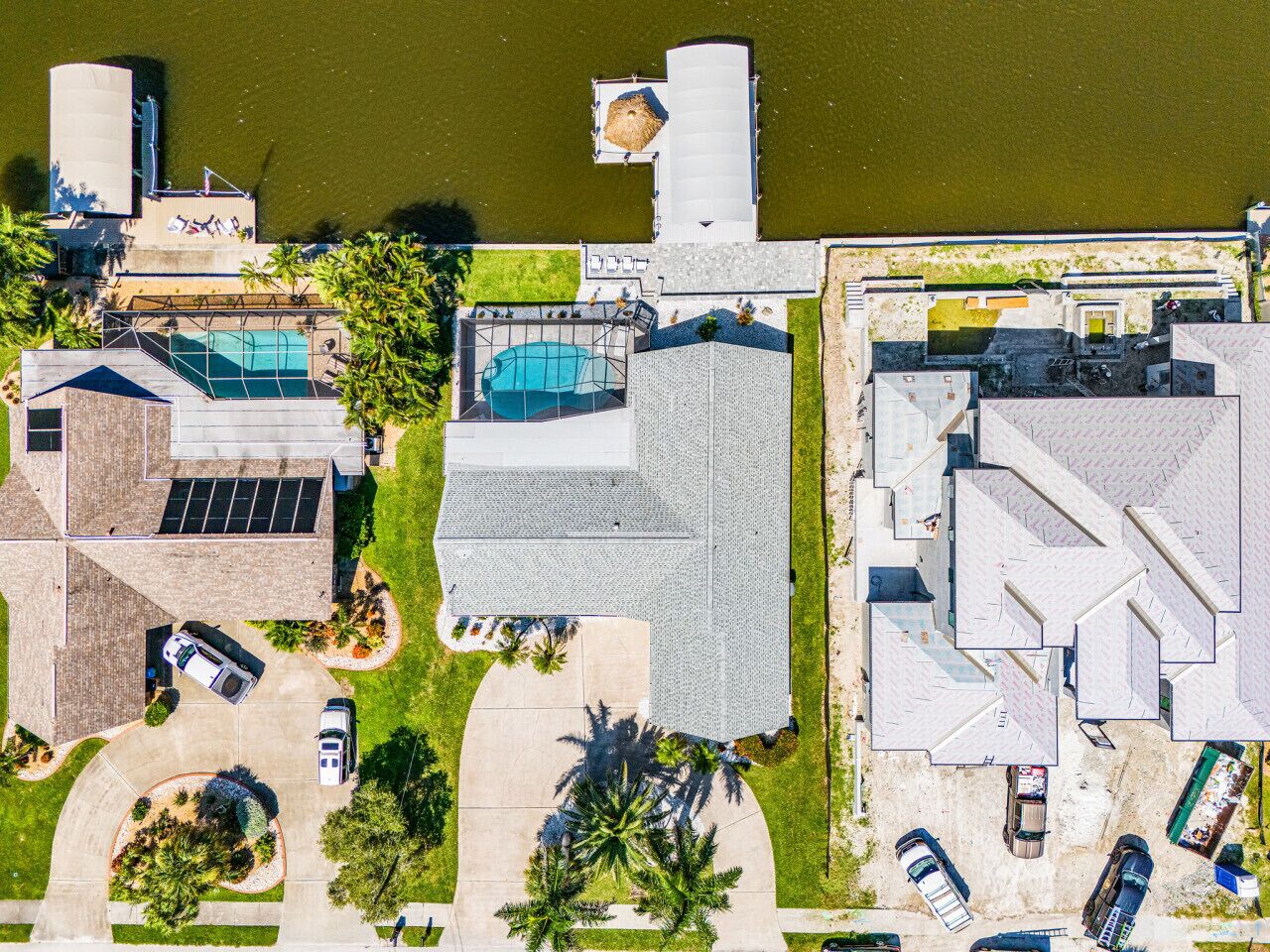 Vue aérienne d’un quartier résidentiel avec des maisons, une piscine et un plan d’eau.
