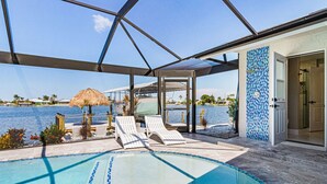 Une piscine avec des chaises longues, un espace abrité et une vue sur la mer.