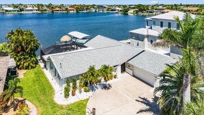 Une propriété située au bord de l’eau, comprenant une grande maison, une piscine et un quai pour bateaux.