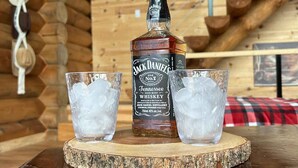 En flaska Jack Daniel’s Tennessee-whisky och två glas fyllda med is, placerade på en underlägg av trä.