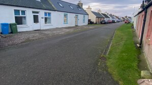 A narrow street lined with white houses with blue trim and pitched roofs.