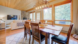 A dining area with a wooden table, chairs, and a hanging light fixture.