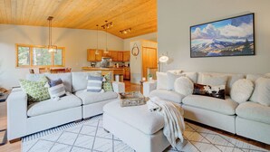 A spacious living area with a wooden ceiling, a large painting, and a cozy seating arrangement.