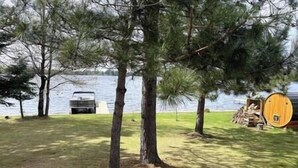 Järvenrantainen alue, jossa on puita, laituri ja puinen rakennelma.