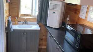 Pieni, käytännöllinen keittiö, jossa on pesuallas, mikroaaltouuni ja jääkaappi.