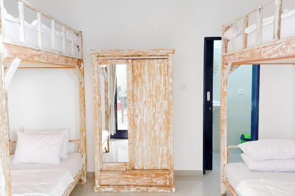 Ein Zimmer mit zwei Etagenbetten, einem Spiegel und einer Tür zu einem weiteren Raum.