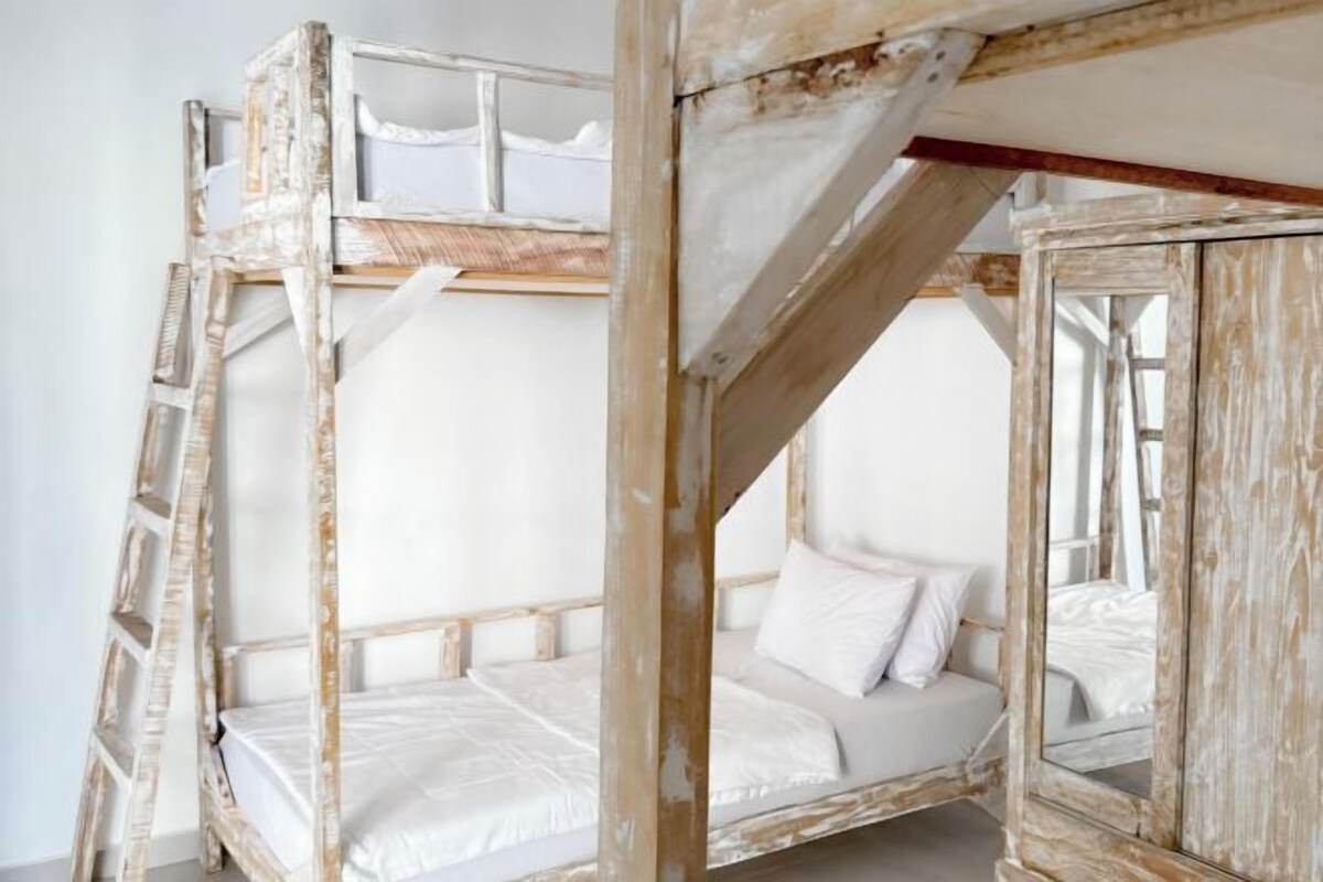 A rustic wooden bunk bed with a ladder, a single white mattress, and a mirror.