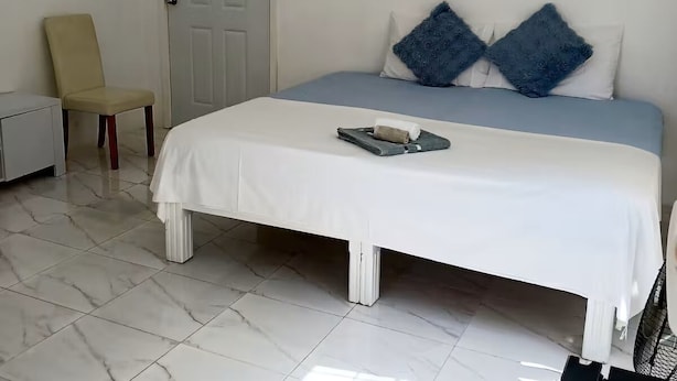 Ein Schlafzimmer mit Bett, Stuhl, Tür und einem Gemälde.