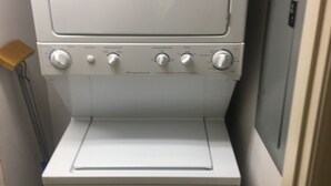 Lavadora y secadora apilables, de color blanco, con puerta frontal, cuatro mandos giratorios y un pequeño panel de control en la parte superior.