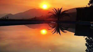 A sunset over a calm body of water with a mountain in the background.