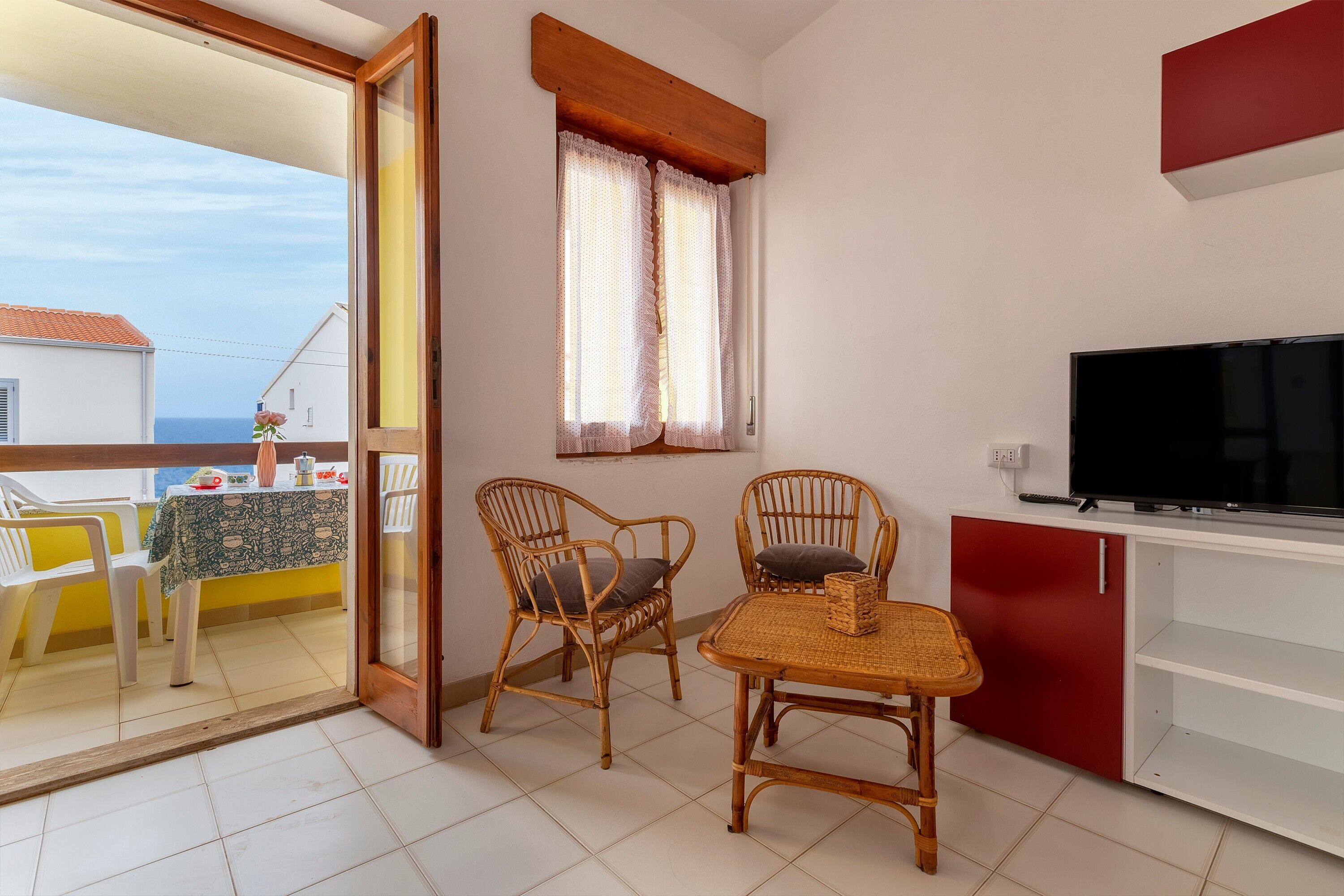 A balcony with a table and chairs, a TV, and a red cabinet.