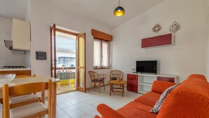 Una sala de estar con sofá, una mesa de comedor con sillas, televisión y una zona de cocina con estufa.