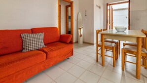 Una habitación con un sofá rojo, una mesa de comedor con sillas y un espejo.