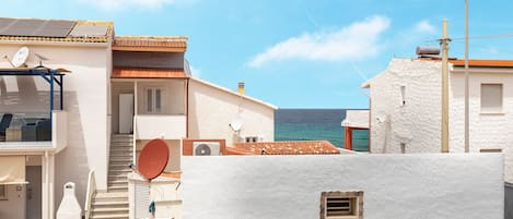 A coastal building with a balcony, satellite dish, and a view of the sea.