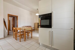 Una cucina con frigorifero, forno e tavolo da pranzo con sedie.