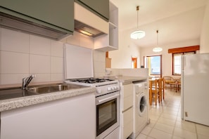 Une cuisine équipée d’un évier, d’une cuisinière, d’un four et d’un lave-linge.